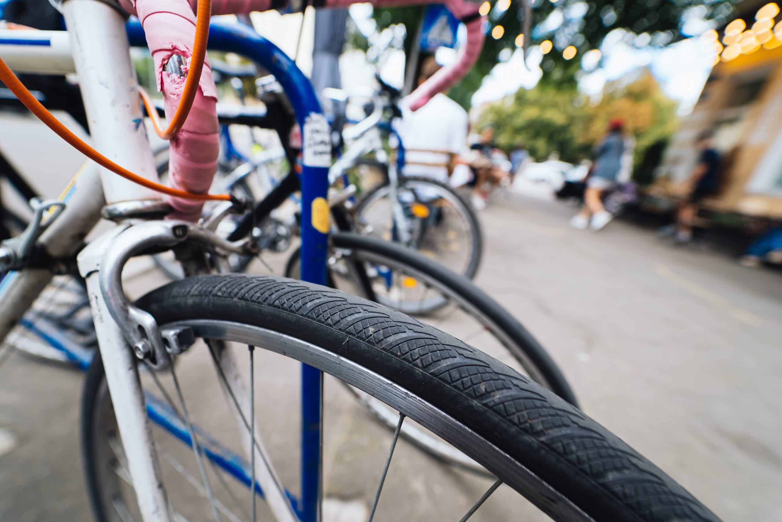 Close-up of bicycle wheels parked on a city street with people in the background