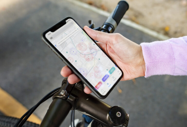 Cyclist checking a navigation app on a smartphone mounted on bicycle handlebars