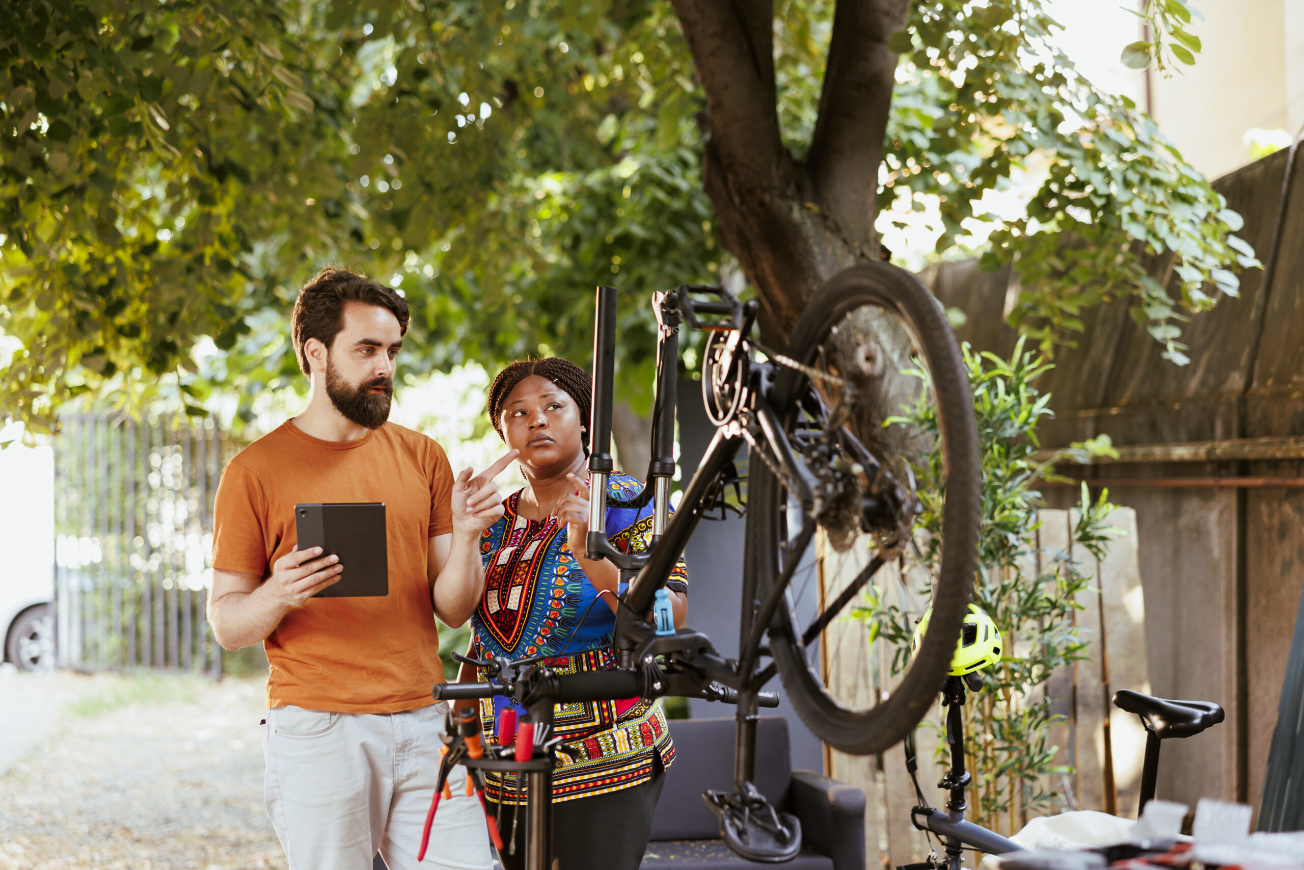 Couple using a tablet for bicycle maintenance outdoors
