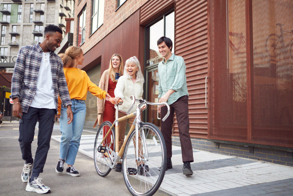 Group of friends walking together on city street with bicycle