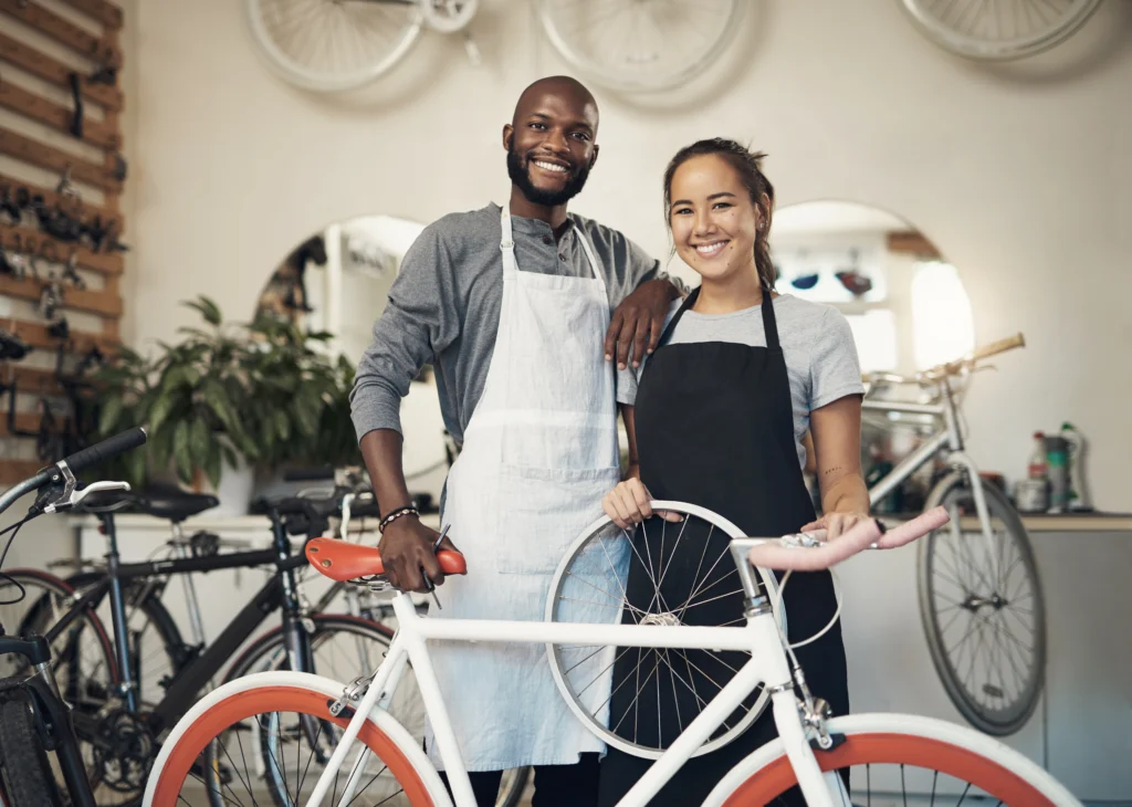 Two bicycle mechanics standing with a bike inside a repair workshop