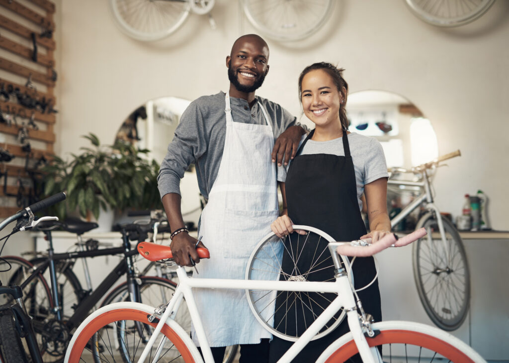 Two bicycle mechanics standing with a bike inside a professional bike repair shop