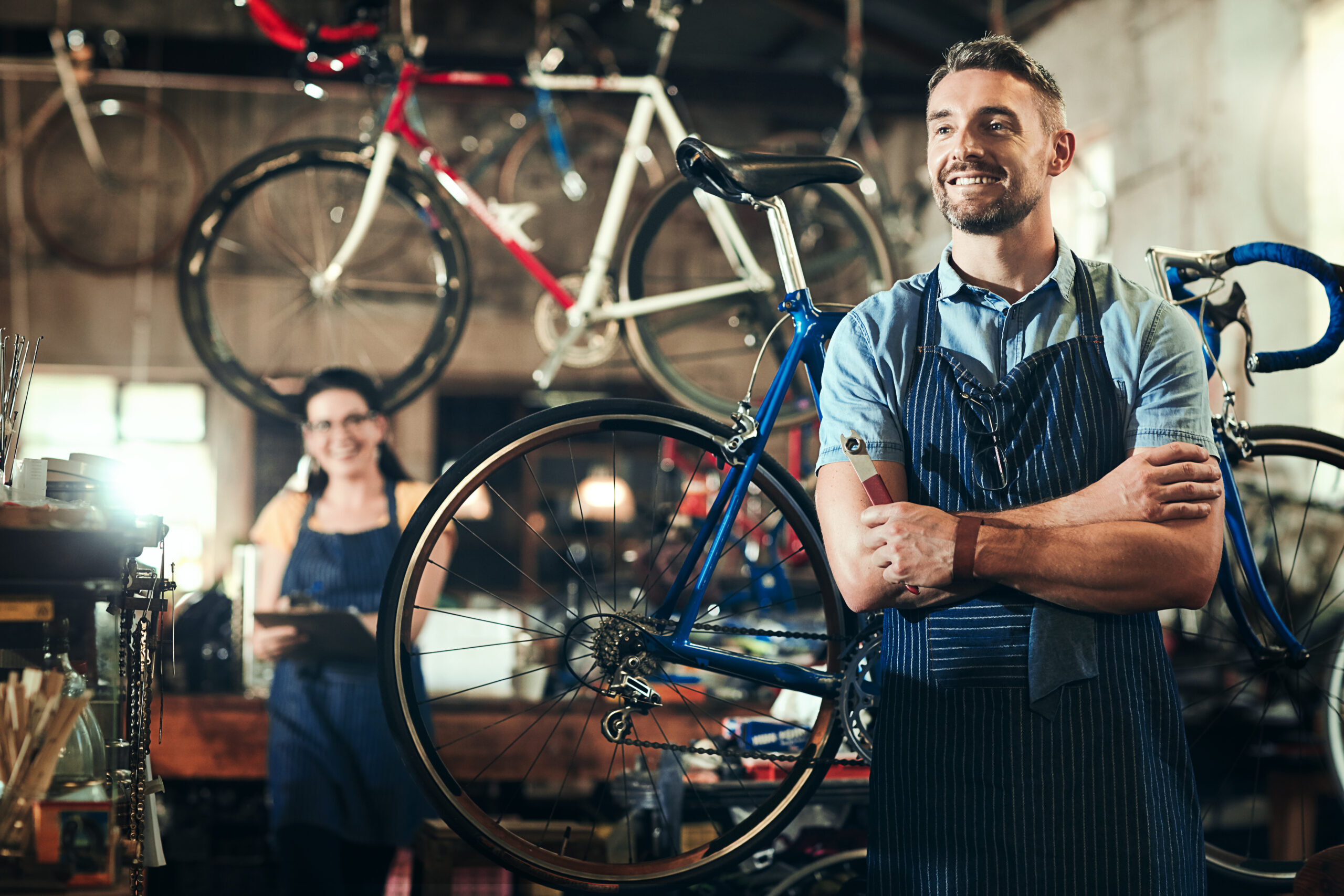 Professional bicycle mechanic standing in a bike repair workshop with a road bike