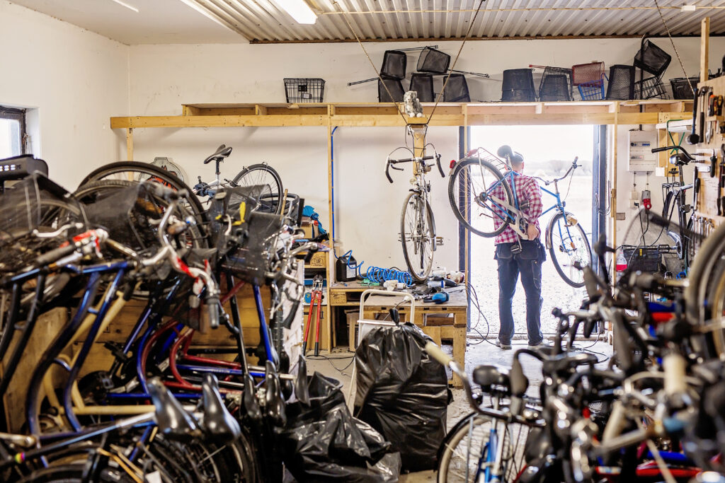 Pedal bicycle mechanic carrying a customer’s bike inside the repair workshop