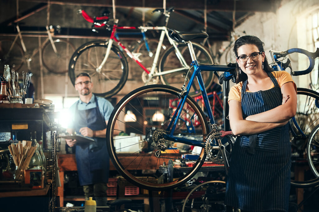 Female bicycle mechanic standing in a bike repair workshop with a bicycle on a repair stand