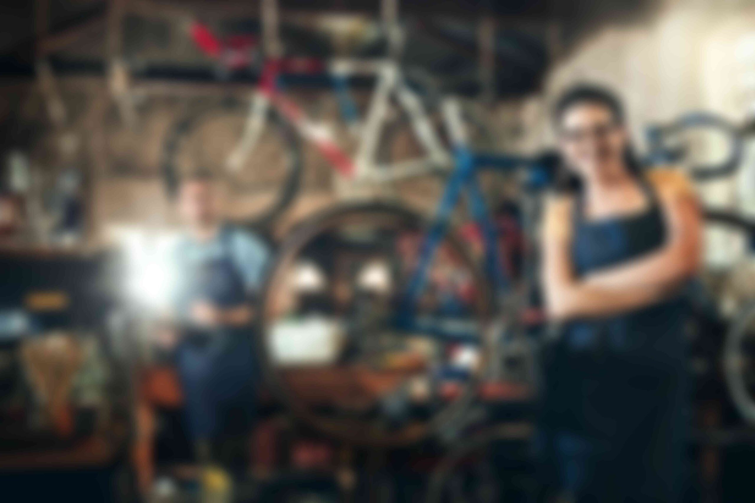 Bicycle mechanics working in a bike repair workshop with bicycles in the background