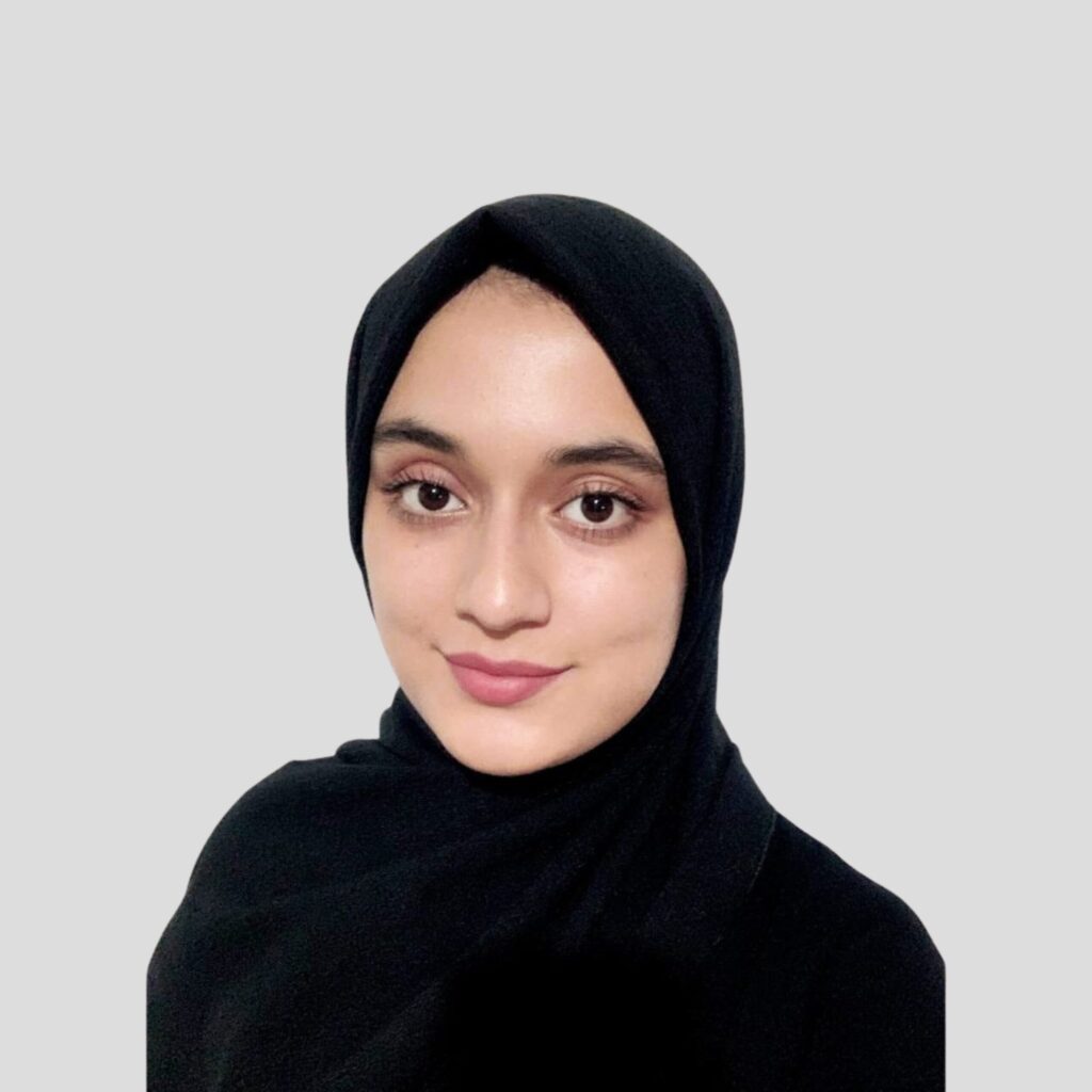 Portrait of a woman wearing a black hijab against a gray studio background